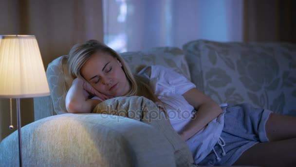 Késő este, a gyönyörű nő elaludt egy kanapén gondoskodó férje magában foglalja neki egy takaró. — Stock videók