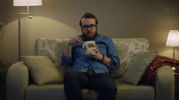 Man sitter på en soffa i vardagsrummet — Stockvideo