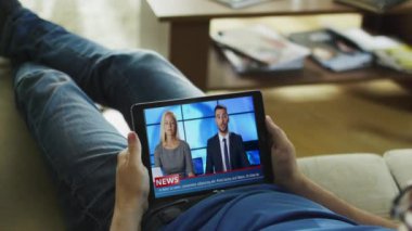 Rahat adam onun kanepe saatler haber yalan onun Tablet bilgisayar üzerinde yayın.