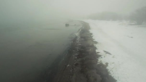 Tiro aéreo de uma costa do mar. É inverno e há nevoeiro e neve em todos os lugares . — Vídeo de Stock