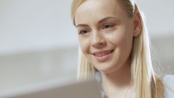 Close-up do rosto de uma jovem mulher bonita, ela trabalha em um laptop, em um ambiente leve . — Vídeo de Stock