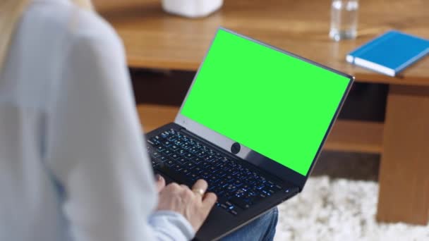 Sobre el tiro de hombro de una mujer que trabaja en un ordenador portátil con pantalla falsa verde en él. Ella sostiene el ordenador portátil en su vuelta . — Vídeo de stock
