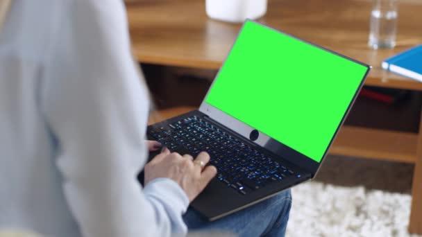 Sobre o ombro tiro de uma mulher segurando tela verde Mock-up Laptop em seu lap . — Vídeo de Stock