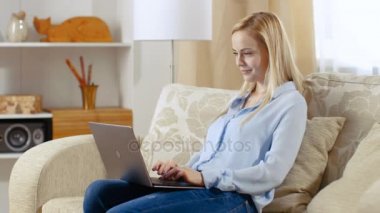 Onu oturma odasında bir kanepede oturan güzel ve genç birbayan. O onu Laptop onun sukut ve eserler üzerinde tutar.