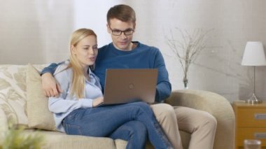 Tatlı çift onların oturma odasında kanepede oturuyor. Onlar Laptop istimal ve gülümseyerek. Tam ışık odam.