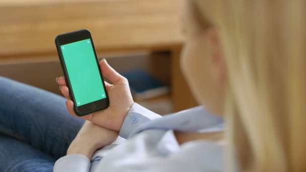 Sobre el tiro de hombro de una mujer sosteniendo un teléfono inteligente en su mano que ha aislado la pantalla verde simulada . — Vídeo de stock