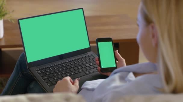 Na ramię strzał z kobieta za pomocą laptopa i trzymając Smart telefon, zarówno mają makiety Green Screen na. — Wideo stockowe