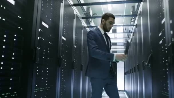 IT-інженер в центрі обробки даних відкриває двері серверної стійки кабінету і підключається до нього за допомогою ноутбука. Проводить діагностику . — стокове відео