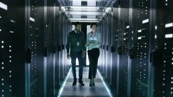 Στο Data Center / Server δωμάτιο μηχανικός διαβουλεύεται με γυναίκα επικεφαλής μηχανικός που κρατά τον υπολογιστή Tablet. — Αρχείο Βίντεο