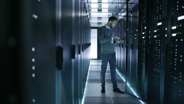 Tecnico IT Lavora sul computer portatile in Big Data Center pieno di server rack. Gestisce la diagnostica e la manutenzione, imposta il sistema . — Video Stock