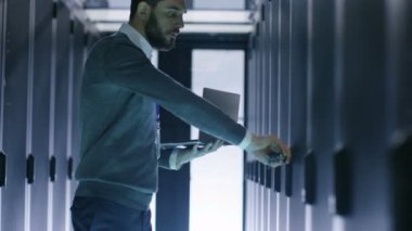 Erkek bu mühendis açılır sunucu kabine Holding Laptop süre. O büyük veri merkezinde çalışıyor