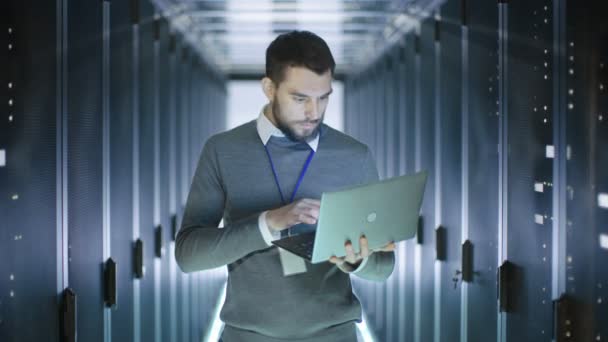 Male Server Engineer Works on a Laptop in Data Center then Smiles. — Stock Video