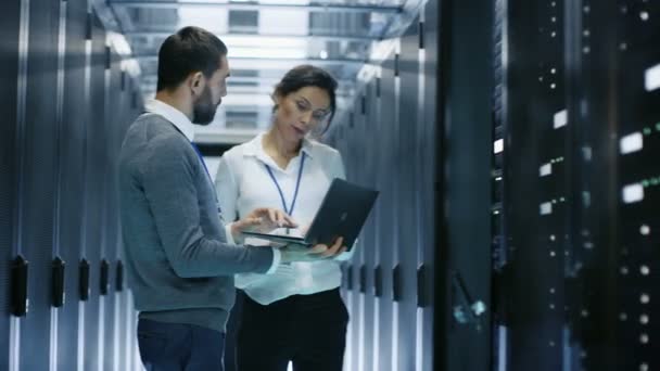 Male IT Specialist Shows Information on a Laptop to Female Server Technician. They're Standing in Data Center. — Stock Video