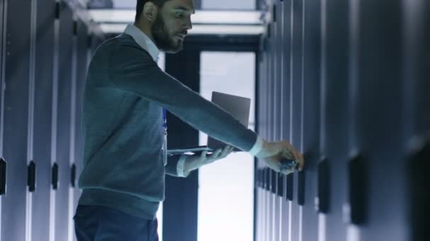 Homme Ingénieur informatique Ouvre armoire de serveur tout en tenant ordinateur portable. Il travaille dans le Big Data Center — Video