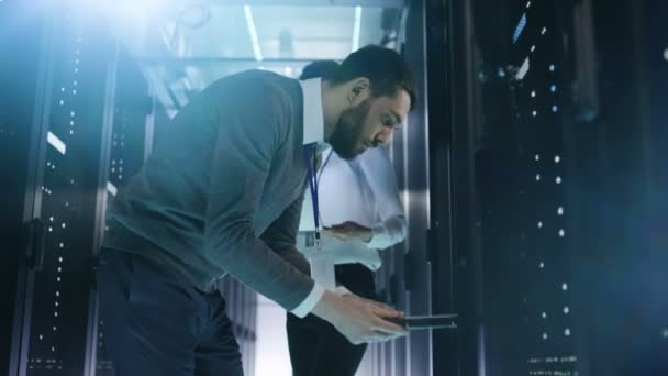 Homme Ingénieur en TI prend les disques durs de Rack Server et les donne à une spécialiste en TI femelle. Ils travaillent dans le Big Data Center. . — Video