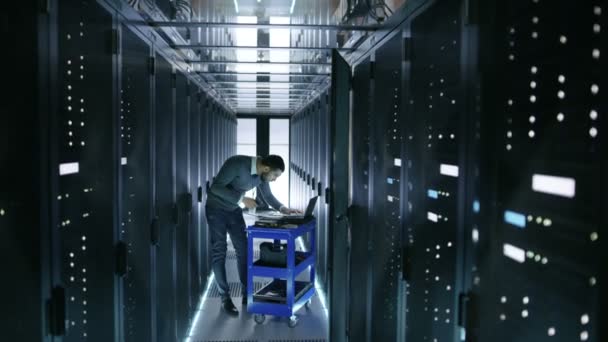 IT Engineer travaille sur un ordinateur portable et scanne les disques durs qui reposent sur un chariot d'accident. Il travaille dans le centre de données .