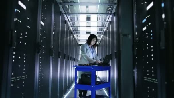 asiatische Ingenieurin arbeitet an einem Crash-Cart-Laptop im großen Rechenzentrum voller Rack-Server.