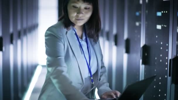 Asian Female IT Engineer Working on a Crash Cart Laptop, She Scans Hard Drives.  She's in Big dataCenter Full of Rack Servers. — Stock Video