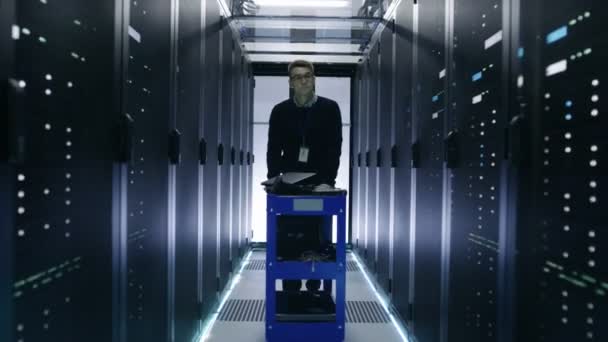 IT Engineer pousse le chariot d'écrasement dans le couloir du centre de données avec des rangées de serveurs de rack .