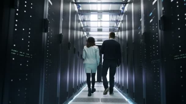 Précédent View of Male and Female IT Engineers Walking in Data Center with Rows of Rack Servers. Ils ont une discussion, elle tient Tablet Computer .