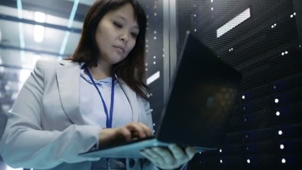 Close-up van vrouwelijke Aziatische het ingenieur die op een Laptop werkt in datacenter vol rackservers. — Stockvideo