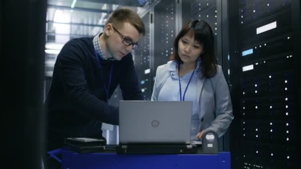 Mand IT Specialist Viser oplysninger om en bærbar computer til kvindelig server tekniker. De står i Datacenter. . – Stock-video