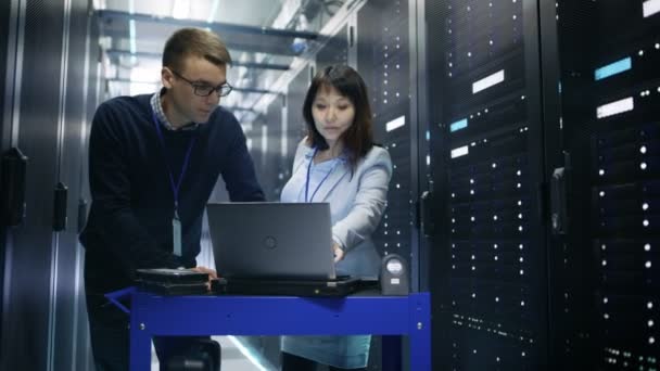 Kaukaski mężczyzna i azjatyckich kobiet Server inżynierów pracę z Crash koszyka Laptop w Big Data Center pełna serwerów stelażowych. — Wideo stockowe