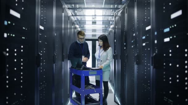 Caucasian Male and Asian Female Server Engineers Working with Crash Cart Laptop in Big Data Center full of Rack Servers. — Stock Video