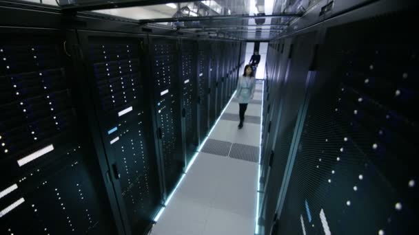 Überwachungskamera-Aufnahmen von asiatischen weiblichen IT-Spezialisten und kaukasischen männlichen Server-Ingenieuren, die Crash Cart schieben. Sie arbeiten im Big Data Center. — Stockvideo