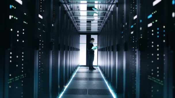 Homme ingénieur informatique travaille sur un ordinateur portable dans un Big Data Center. Les rangées de serveurs de rack sont vues .