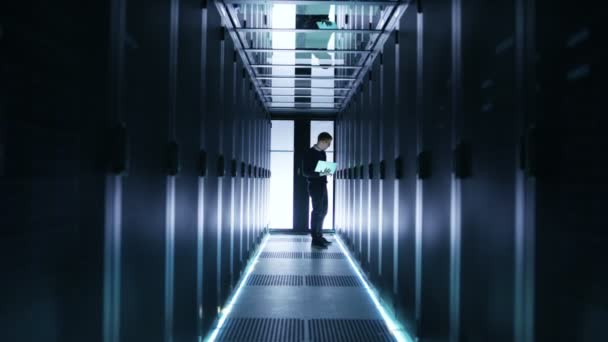 Homme ingénieur informatique travaille sur un ordinateur portable dans un Big Data Center. Les rangées de serveurs de rack sont vues .