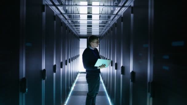 Male IT Engineer Works on a Laptop in a Big Data Center. Rows of Rack Servers are Seen. — Stock Video