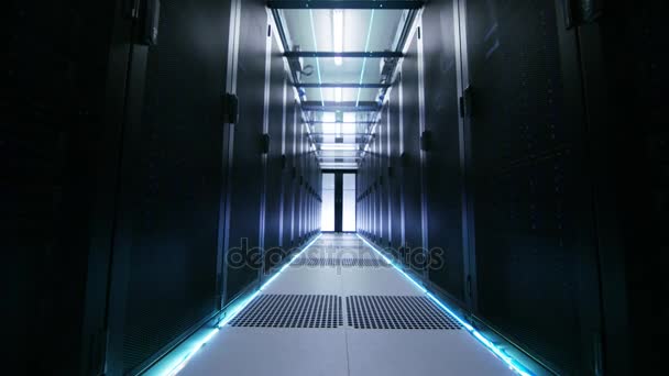 La fotocamera si muove attraverso un data center illuminato atmosfericamente con righe di server rack e soffitti in vetro . — Video Stock