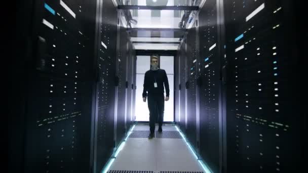 Après coup de l'ingénieur informatique marchant dans le couloir du centre de données avec des rangées de serveurs de rack .