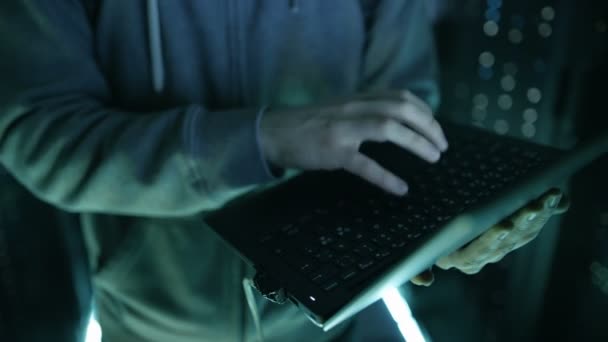Absteigender Schuss eines maskierten Hackers, der Laptop in der Hand hält und Firmenserver hackt. — Stockvideo