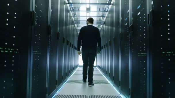 Vue arrière de l'ingénieur informatique marchant à travers le centre de données avec des serveurs de rack de travail . 