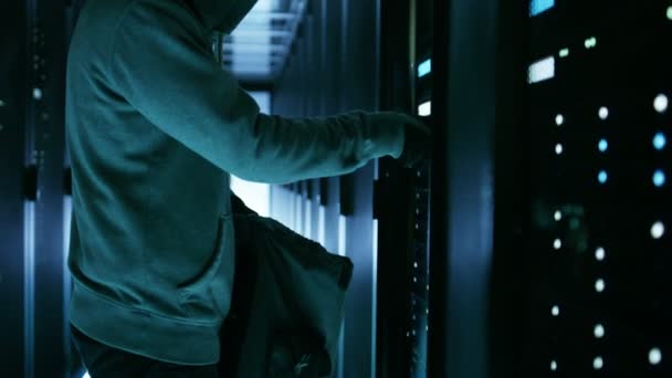 Hacker in een Hoodie steelt harde schijven van Corporate Data Center-rackserver. — Stockvideo