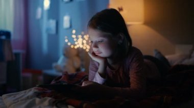 Onun odasına gece, sevimli küçük kız yatak kullanır Smartphone'da yatıyor. Açık onun gece lambası.