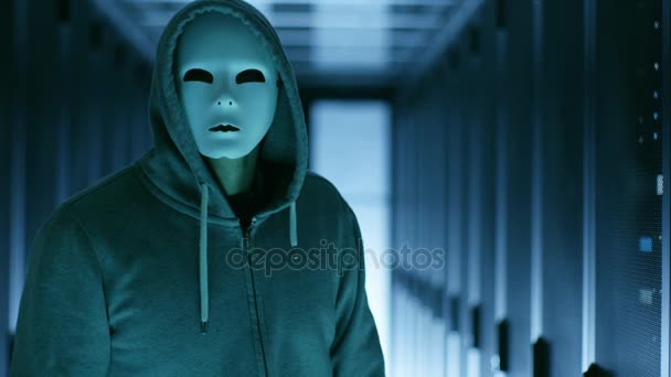 Un hacker mascherato con una felpa con cappuccio si allontana dalla telecamera. E 'in un data center. . — Video Stock