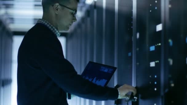 ИТ-инженер держит ноутбук с диаграммами на экране и открытом сервере . — стоковое видео