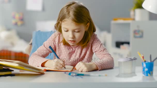 Diligent joven chica hace la tarea mientras se sienta en su habitación . — Vídeo de stock