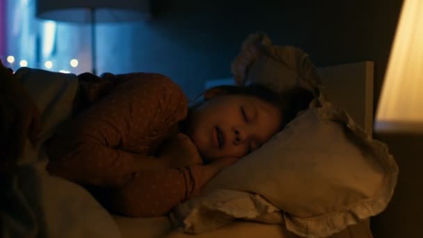 Tatlı küçük kız yatağında geceleri, onun annesi Tucks onu battaniyeye uyur. — Stok video