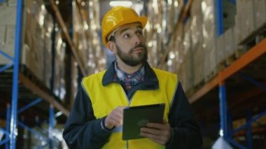 Sabit şapka Tablet bilgisayar ile Denetçi mal ambarındaki sayar. O mal ile depolama rafları satırlarının size yürür.