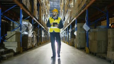 Sabit şapka Tablet bilgisayar ile Denetçi mal ambarındaki sayar. O mal ile depolama rafları satırlarının size yürür.