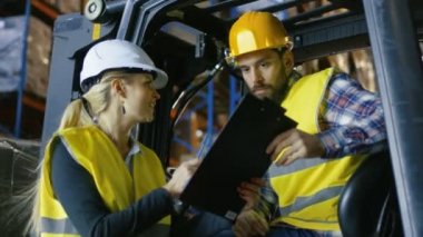 Kadın Yöneticisi sürücü Forklift için çalışma atamasını sağlar. Büyük bir depodalar palet raflar dolu.