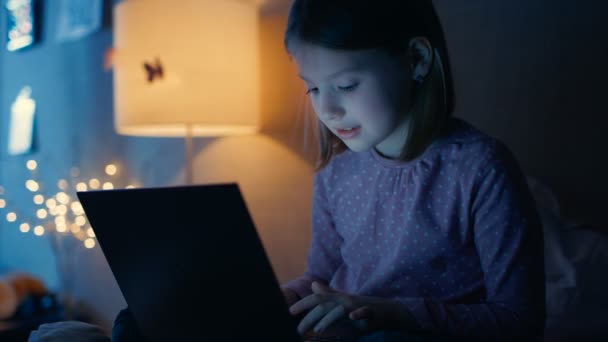 Slimme jonge meisje In haar slaapkamer laat in de avond zit op haar Bed met Laptop en iets interessants te typen. Haar nacht Lamp brandt. — Stockvideo