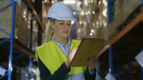 Kvinnliga Surveyor bär Hard Hat använder Tablet PC för inspektion i stora lager med pallställ i det. — Stockvideo