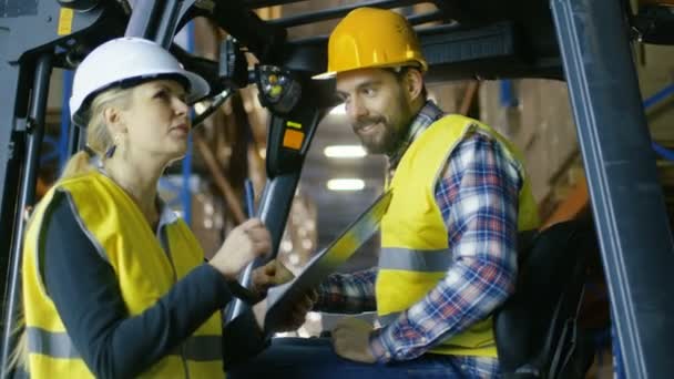 Il supervisore donna assegna lavoro al conducente del carrello elevatore. Sono in un grande magazzino pieno di scaffali per pallet. . — Video Stock