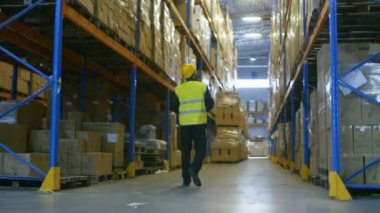 Aşağıdaki Shot bir ambar işçinin depolama rafları satırları arasında yürüyüş zor şapka.