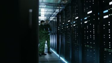 Veri merkezinde iki askeri açık Server raf kabine ile çalışıyor. Bir askeri Edition dizüstü tutar.